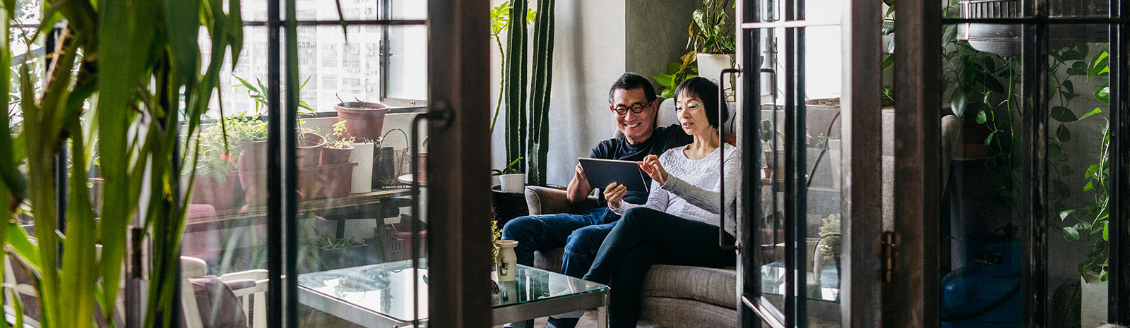 Two people on a couch looking at a tablet together.