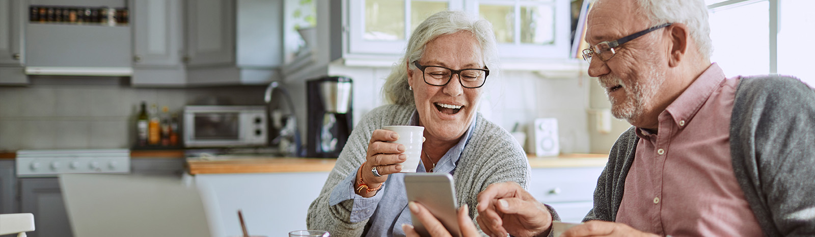 Couple at kitchen table looking at cell phone