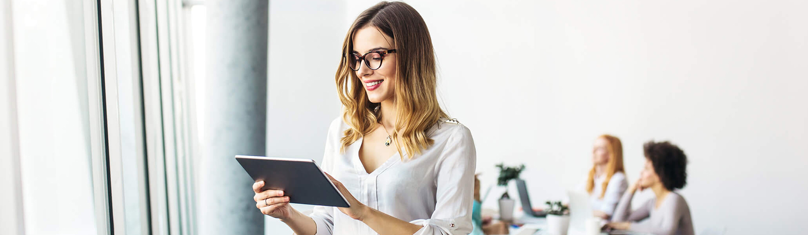 Woman in a modern office setting using a tablet.